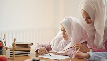 Young Asian Muslim Hijab teaching her student to painting in her art class